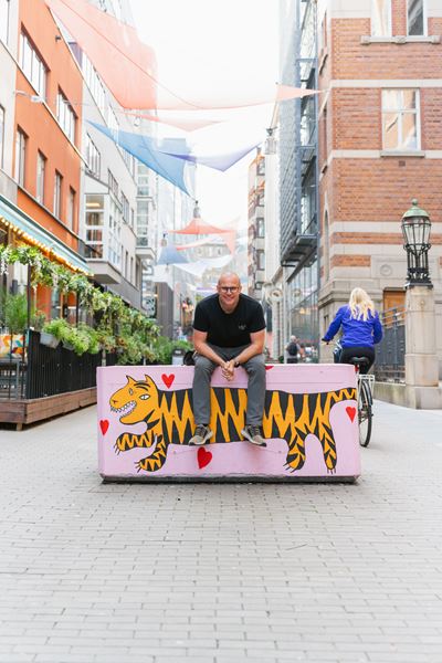 Hombre sentado en un macetero mirando y sonriendo a camara
