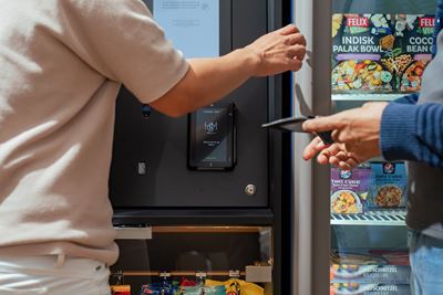 Dos personas pagando en una maquina expendedora