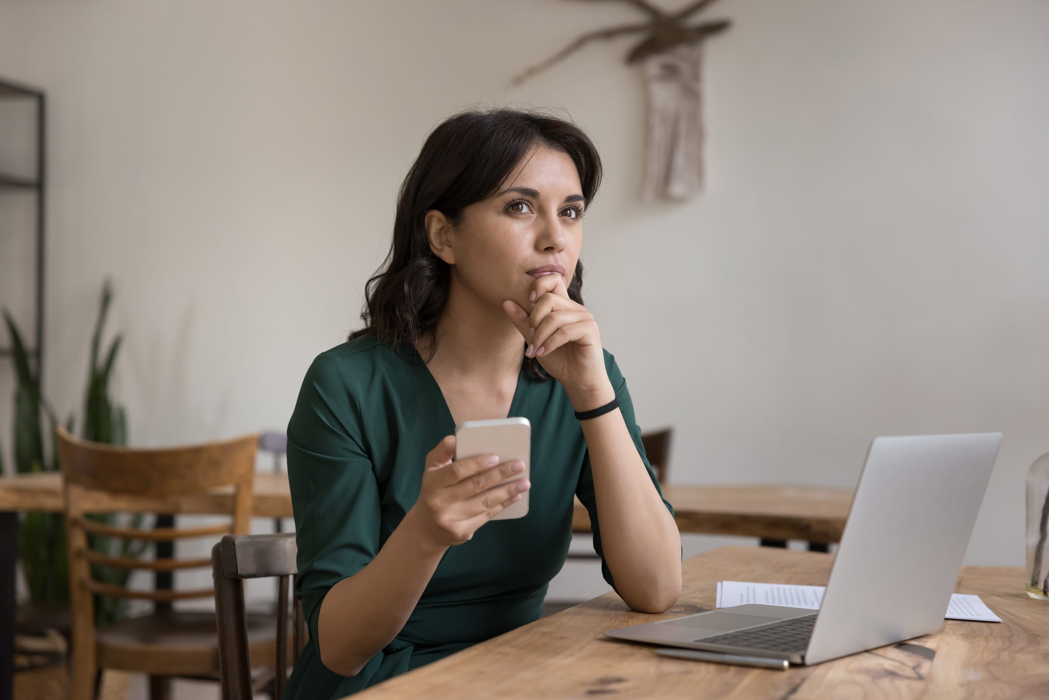 chica pensando en un restaurante con un ordenador y un movil sobre el analisis dafo de su restaurante