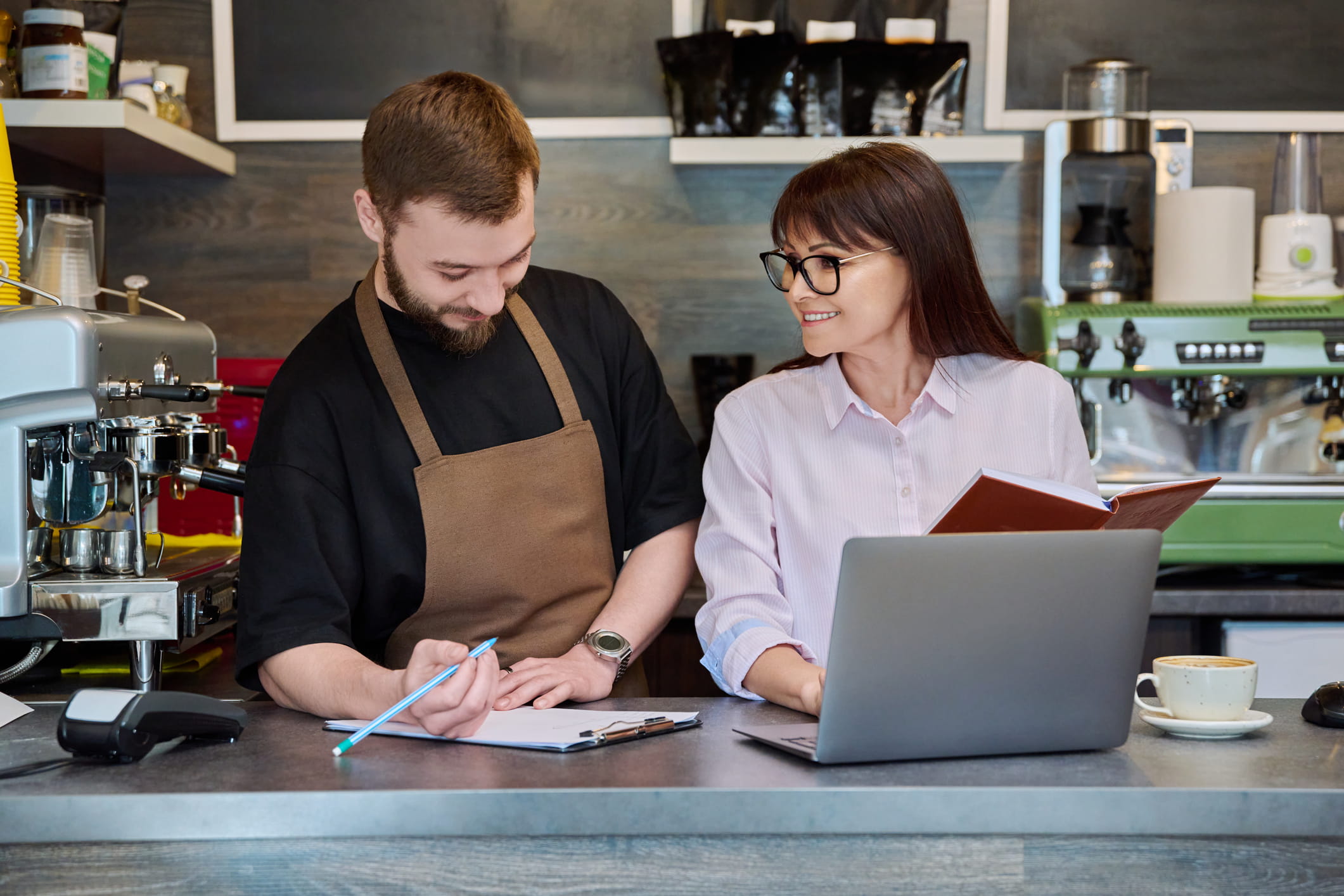pareja en una cafeteria con un portatil y papeles