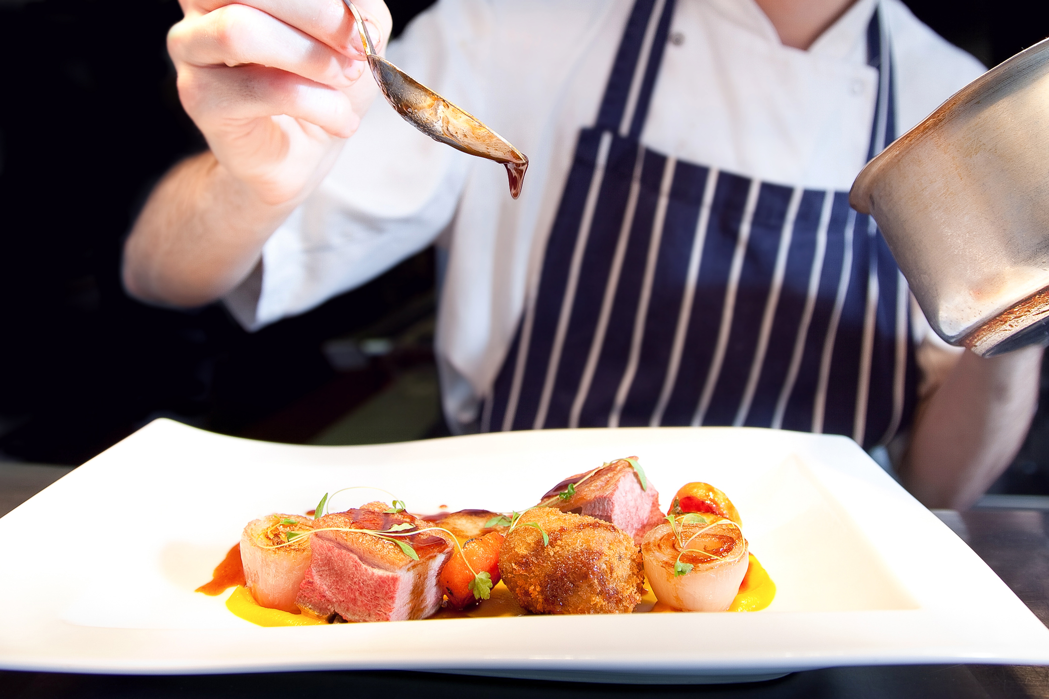 camarero echando salsa en un plato