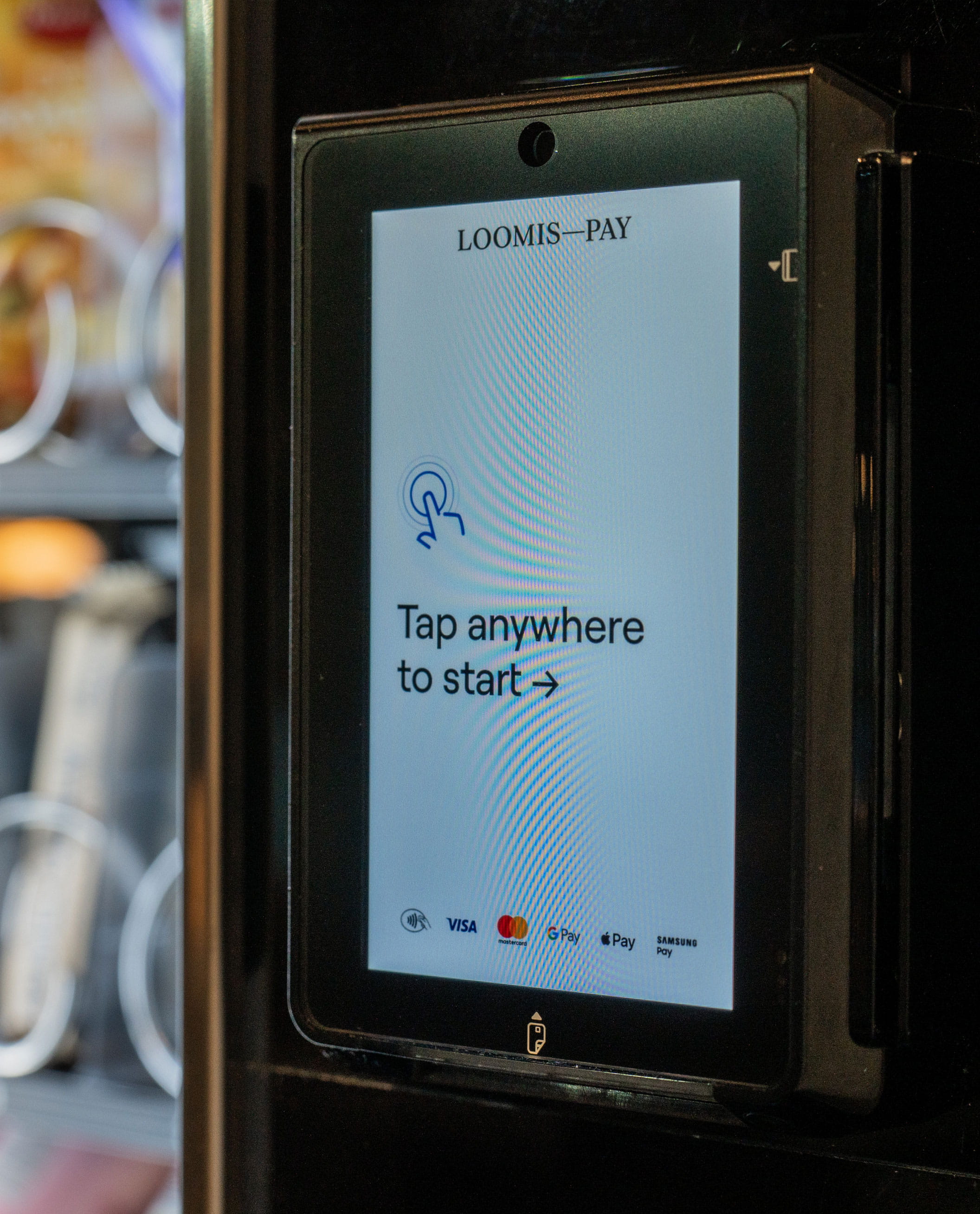 Dispositivo desatendido en primer plano con el mensaje "Tap anywhere to start" (Toca en cualquier parte para empezar).