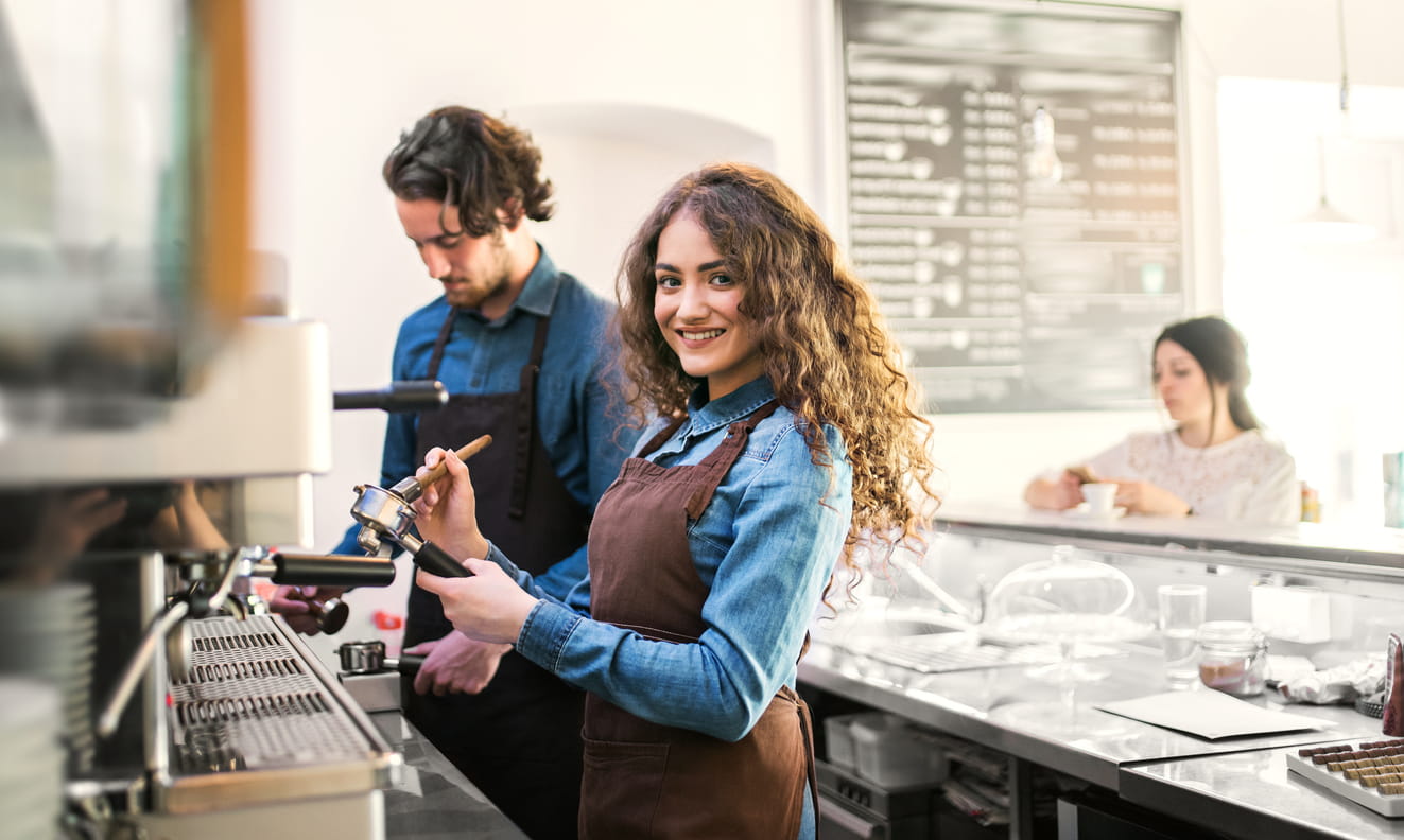 chica feliz haciendo cafe en cafeteria