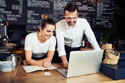 Mirando un ordenador portatil dos personas en un local